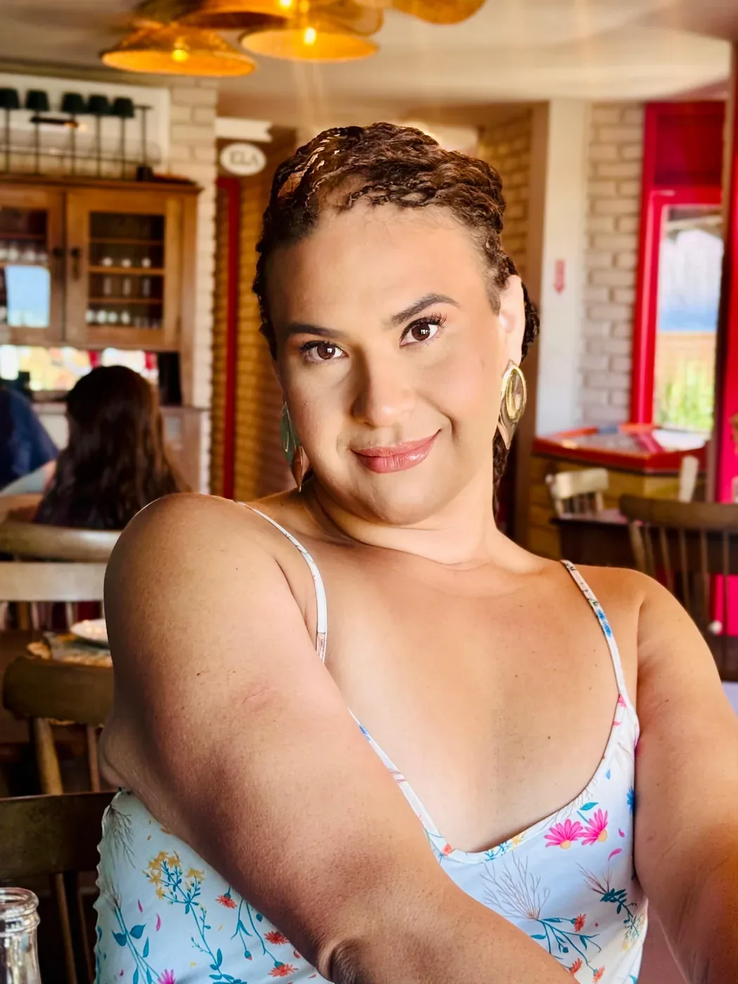 Mathy Lemoss sorrindo, apoiada em uma mesa